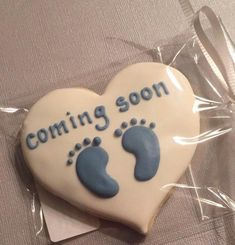 a cookie shaped like a heart with footprints and the words coming soon written on it