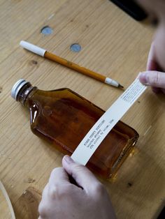 a person holding a bottle with a note attached to it next to a pencil and eraser