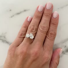 a woman's hand with a diamond ring on top of her finger and the other hand holding an engagement ring