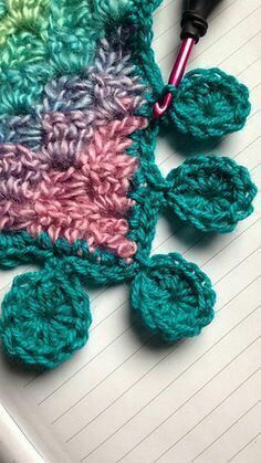 a crocheted flower is laying on top of a notebook with a pen in it