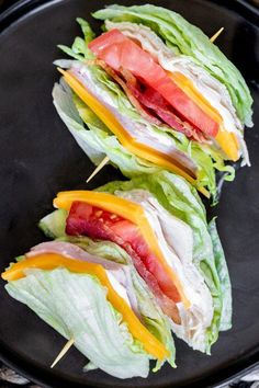 two lettuce wraps with cheese and tomato on them sitting on a black plate