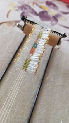 two pairs of knitting needles with beading attached to each other on top of a piece of fabric