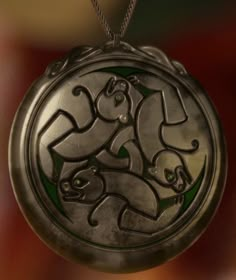 a silver locke with an image of two cats on it's face and green eyes