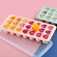 two plastic trays filled with different colored candies on top of a pink and blue surface