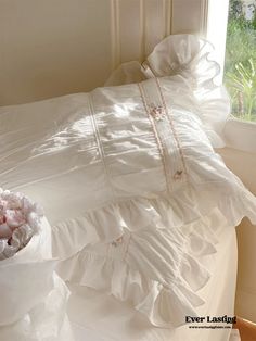 a white bed sitting next to a window covered in plastic bags and pink flowers on top of it