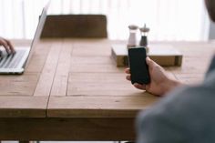 a person sitting at a table with a laptop and cell phone in front of them