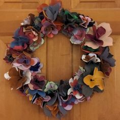 a wreath made out of paper flowers on a door