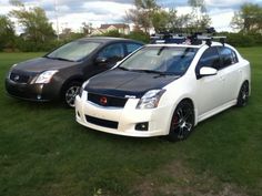 two cars are parked in the grass with their lights on and one has a camera strapped to it's roof