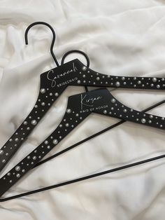 three black metal hangers with personalized names on them, sitting on a white sheet