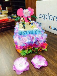 there is a cake that has been decorated with flowers and mickey mouse figurines