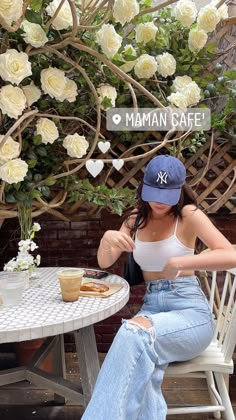 a woman sitting at a table with a plate of food in front of white roses