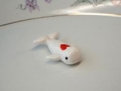 a small white fish with a red heart on it's tail sitting on a plate