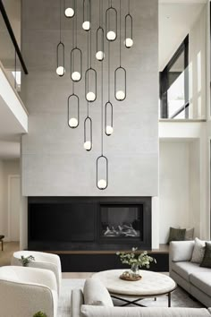 a modern living room with white furniture and large chandelier hanging from the ceiling