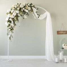 a wedding arch decorated with white flowers and greenery