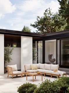 a white couch sitting on top of a patio next to a wooden table and chairs