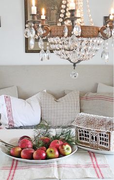 a table topped with apples and a plate filled with fruit next to a chandelier