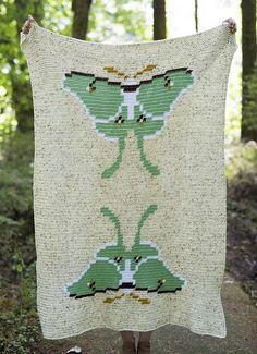 a woman is holding up a blanket in the woods