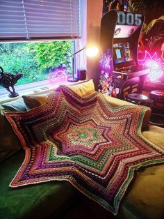 a crocheted blanket sitting on top of a couch in front of a window