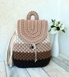 a brown and black purse sitting on top of a wooden table next to a vase