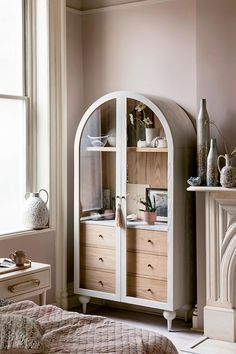 a room with a bed, dresser and fireplace in it's corner area next to a window