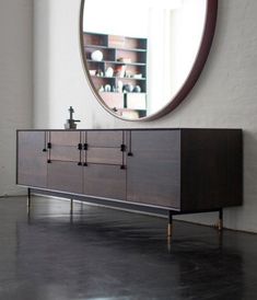 a large round mirror hangs above a modern sideboard