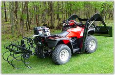 a red four - wheeler parked in the grass with a plow attached to it