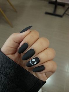 a woman's hand with black nail polish and skull on it