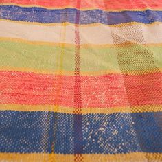 a multicolored blanket is laying on top of a tablecloth with an orange, blue, green, yellow and red stripe pattern