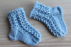 two blue knitted socks sitting on top of a wooden table