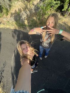 two women standing next to each other with their hands in the air and one pointing at something