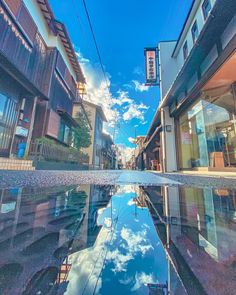 an empty street with buildings and clouds reflected in the water