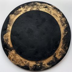 a black and gold plate sitting on top of a white table next to a wall