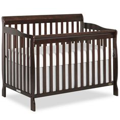 a baby crib with white sheets on the bottom half and brown wood trimmings