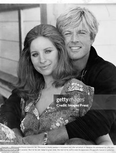 an old black and white photo of a man hugging a woman on the back of a bench