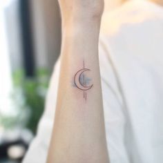 a woman's wrist with a small crescent tattoo on the left side of her arm