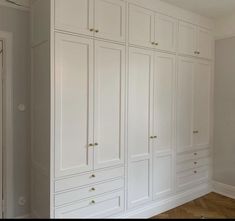 an empty room with white cupboards and wood flooring in the middle of it