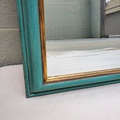 a large blue mirror sitting on top of a white floor next to a building with a brick wall