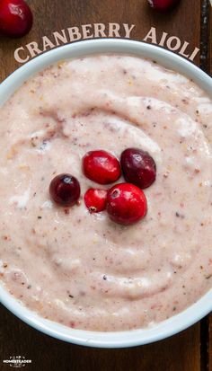 cranberry aioli in a white bowl on a wooden table with cherries