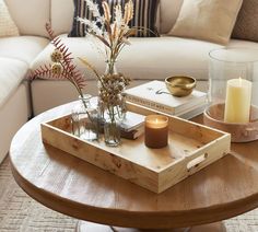 a coffee table with candles, flowers and books on it in front of a couch