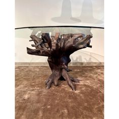 a table made out of driftwood with glass top on carpeted floor in front of white wall