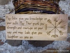 a wooden sign with writing on it sitting in front of a stone wall next to a wicker basket