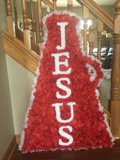 a red and white sign with the word jesus on it in front of some stairs