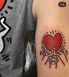 a person with a tattoo on their arm holding a red heart in the middle of his arm