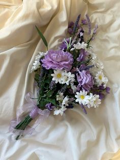 a bouquet of purple and white flowers on a bed