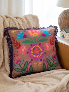 a decorative pillow on a chair next to a window