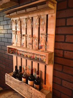 wine glasses and bottles are lined up on a shelf in front of a brick wall