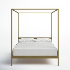 a white bed with a gold frame and pillows on the bottom, in front of a white wall