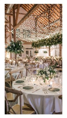 the tables are set with white linens and greenery for an elegant wedding reception