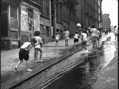 children playing in the water on a city street