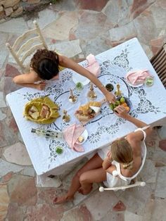 two women sitting at a table with food on it